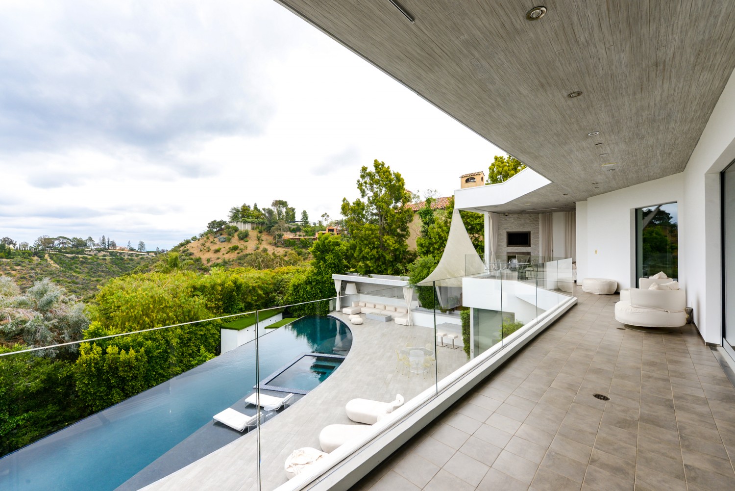 Expansive upper terrace with glass railings overlooking the infinity-edge pool, cabana, and canyon views.