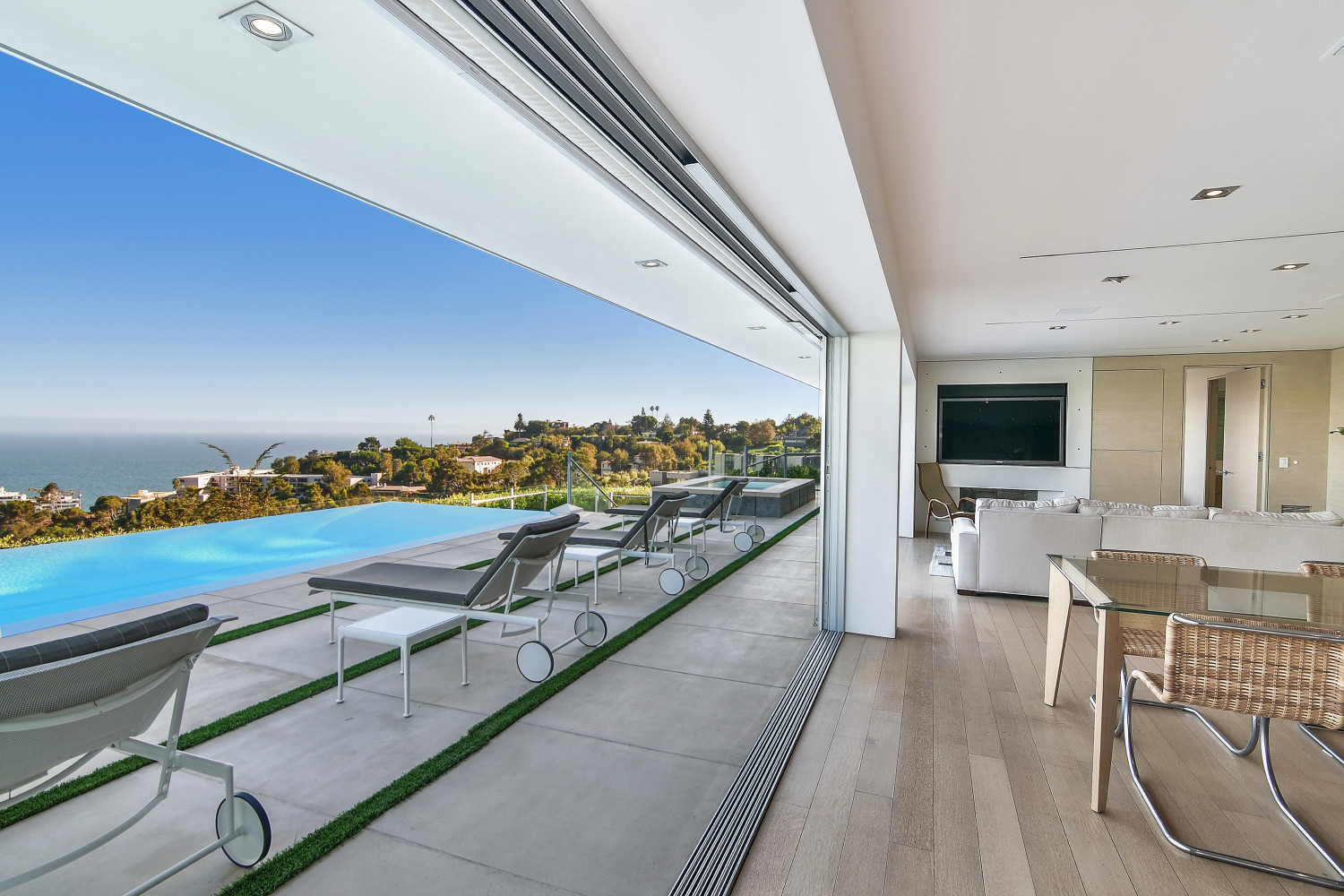 Bright open living room with retractable glass walls overlooking the infinity-edge pool and Pacific Ocean.