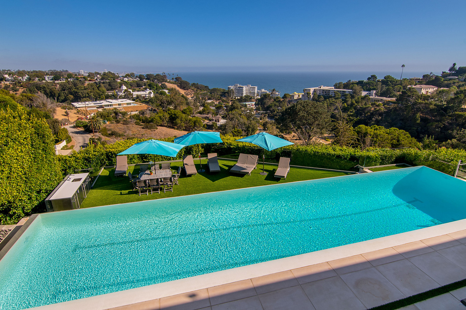 Private lawn and outdoor lounge overlooking the Pacific Ocean at a modern Pacific Palisades estate rental.