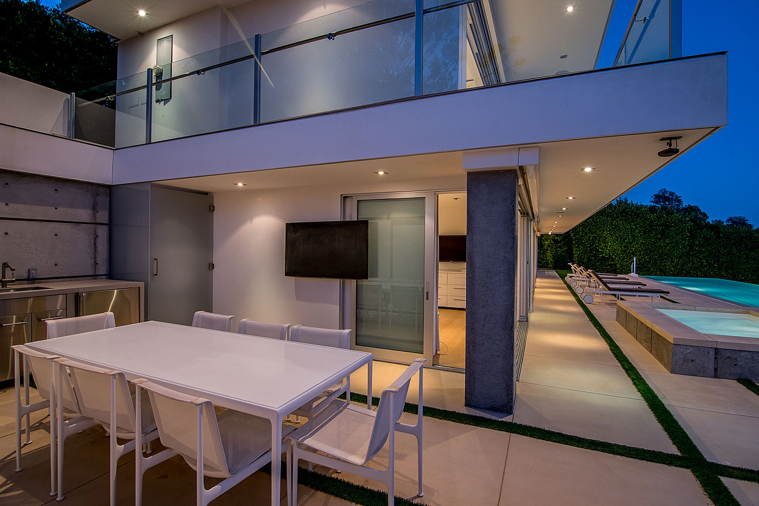 Outdoor dining terrace with ocean views beside the infinity pool at a modern Pacific Palisades estate.