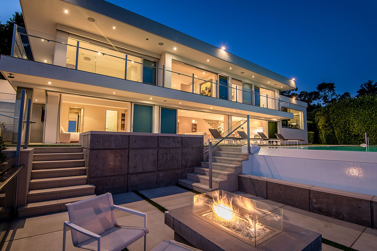Infinity-edge pool, outdoor fire feature, and contemporary architecture at a modern Pacific Palisades private estate overlooking the Pacific Ocean.