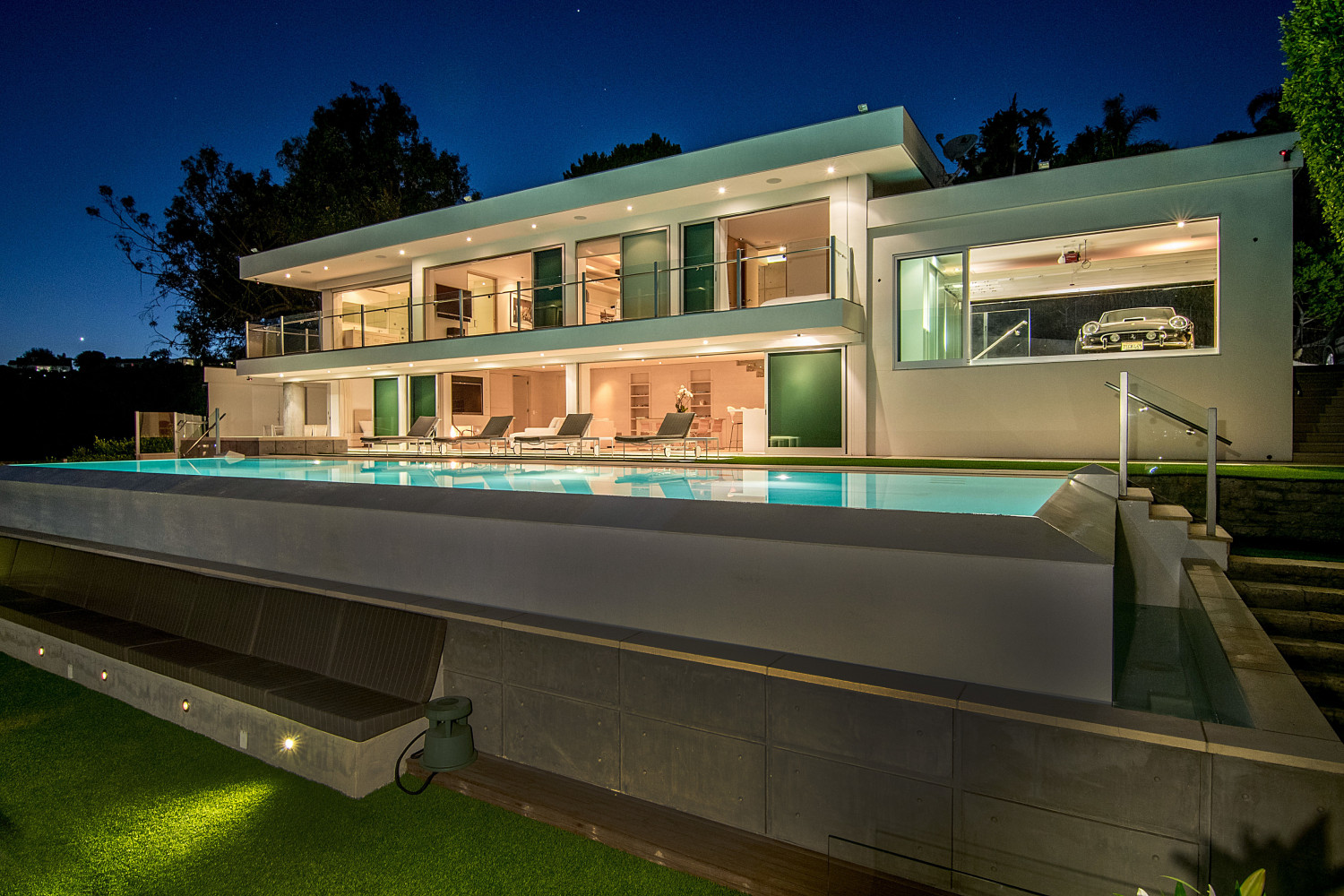 Contemporary Pacific Palisades private estate with an infinity-edge pool, modern architecture, floor-to-ceiling glass, and elegant outdoor entertaining spaces at twilight.
