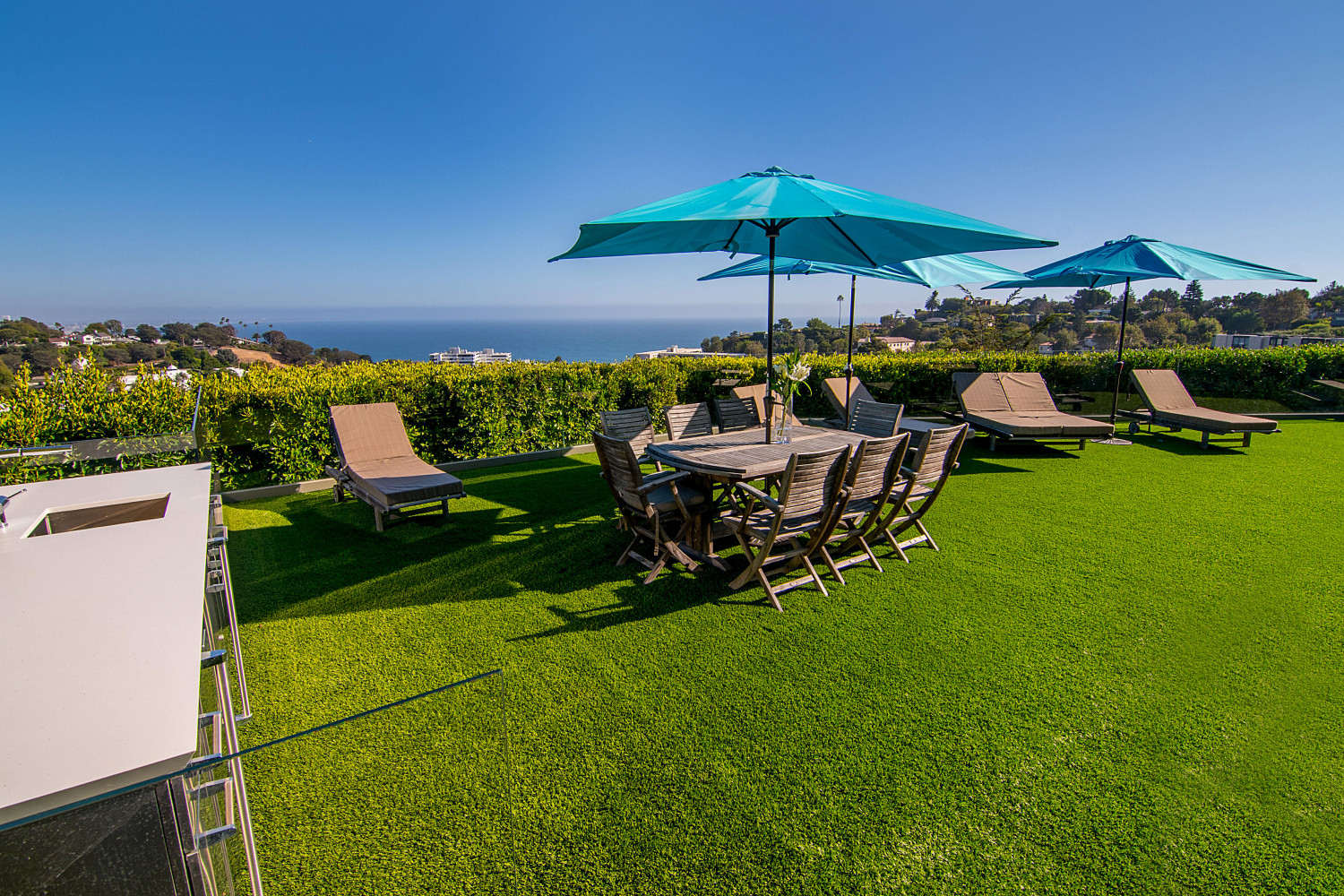 Private lawn and outdoor lounge overlooking the Pacific Ocean at a modern Pacific Palisades estate rental.
