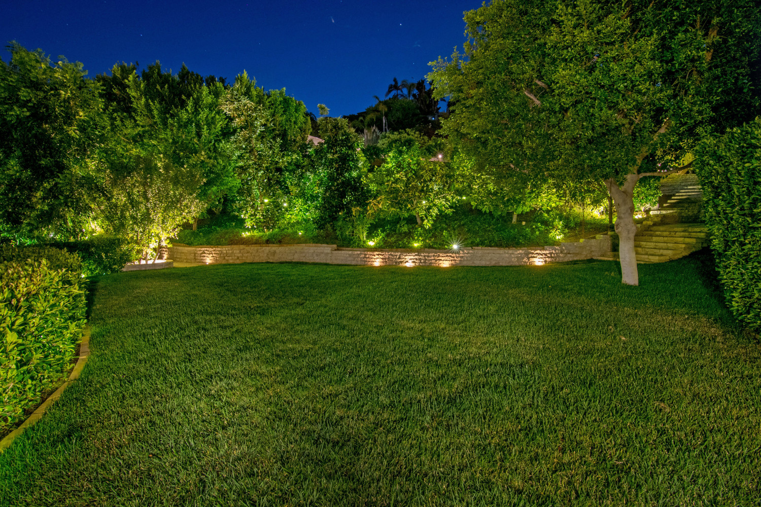 Private landscaped garden and lawn surrounded by mature greenery at a Pacific Palisades estate rental.