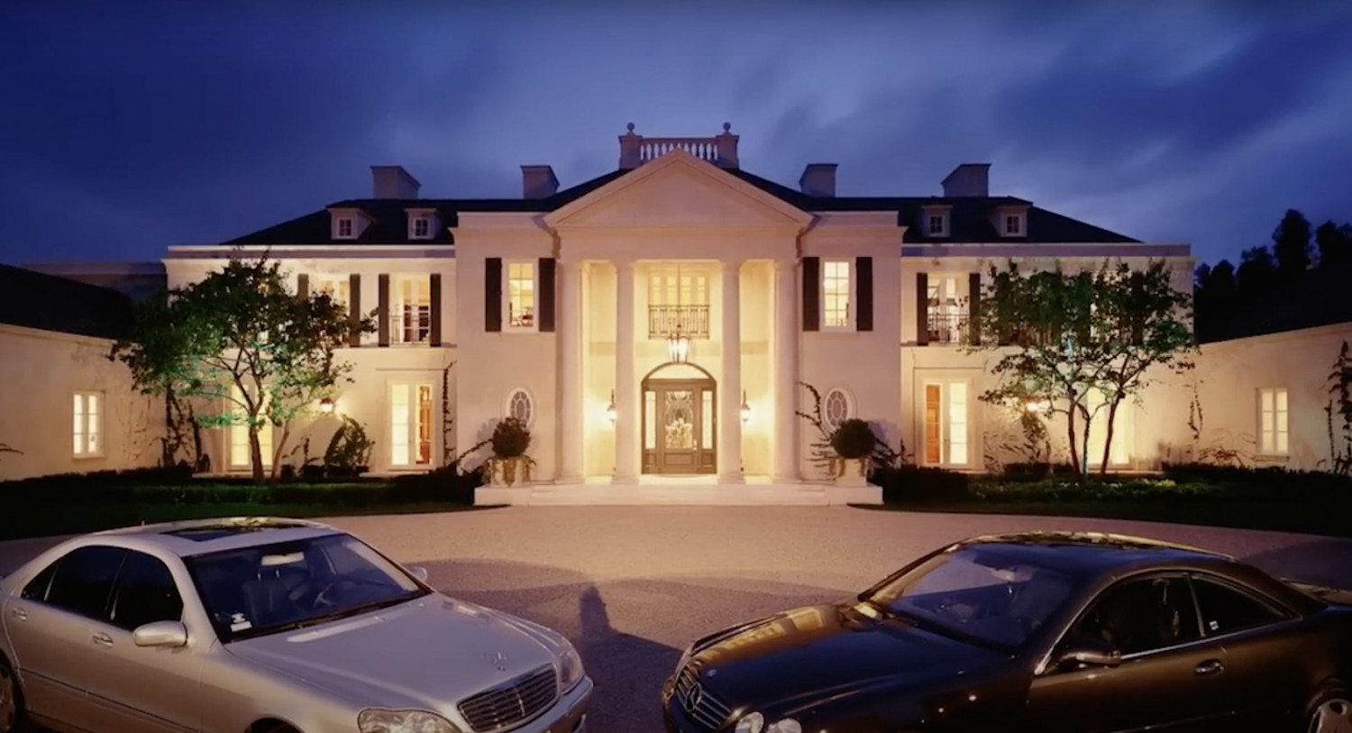 Illuminated front entrance of a luxury French-inspired Bel Air estate with a grand motor court.